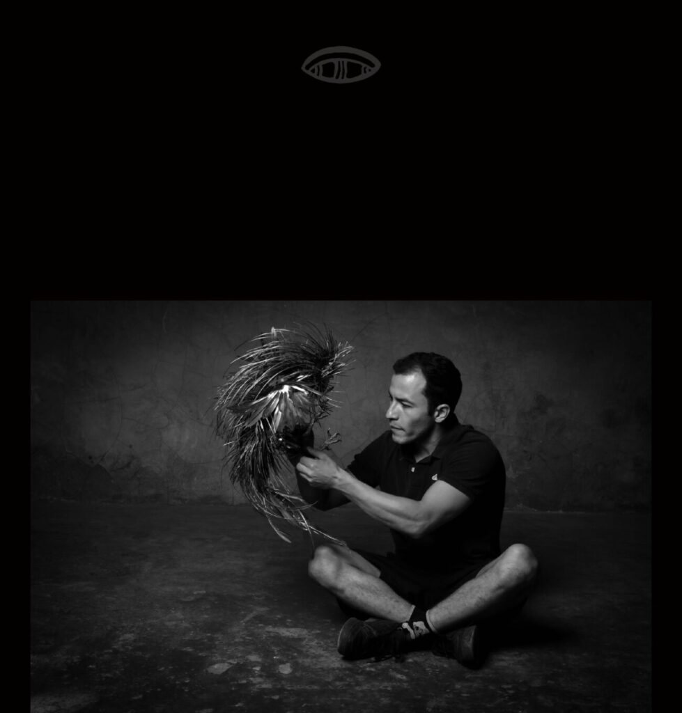 man sitting crossleg contemplationg his bronze metal rooster sculpture